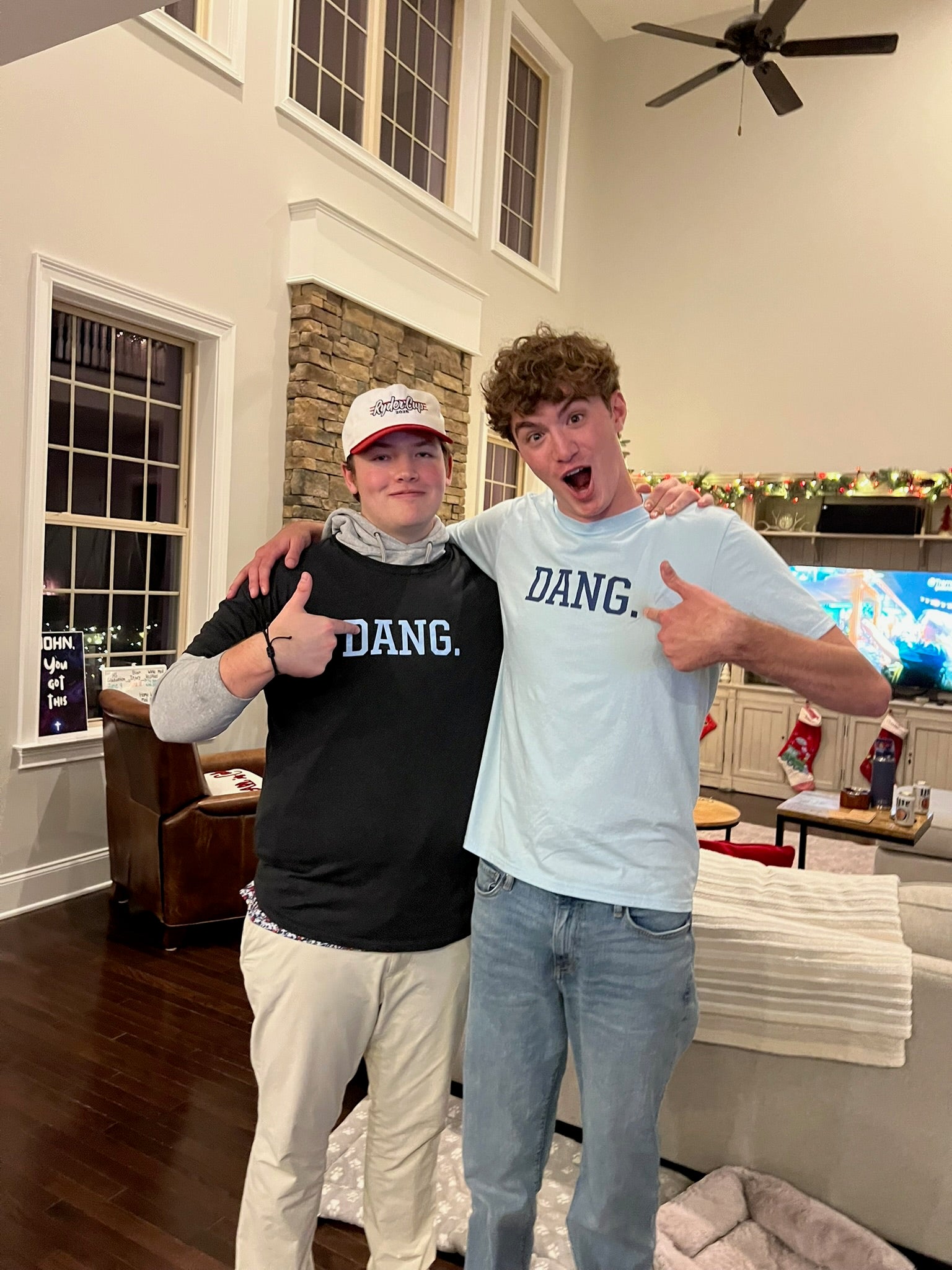 Two people wearing 'DANG' shirts in a living room.